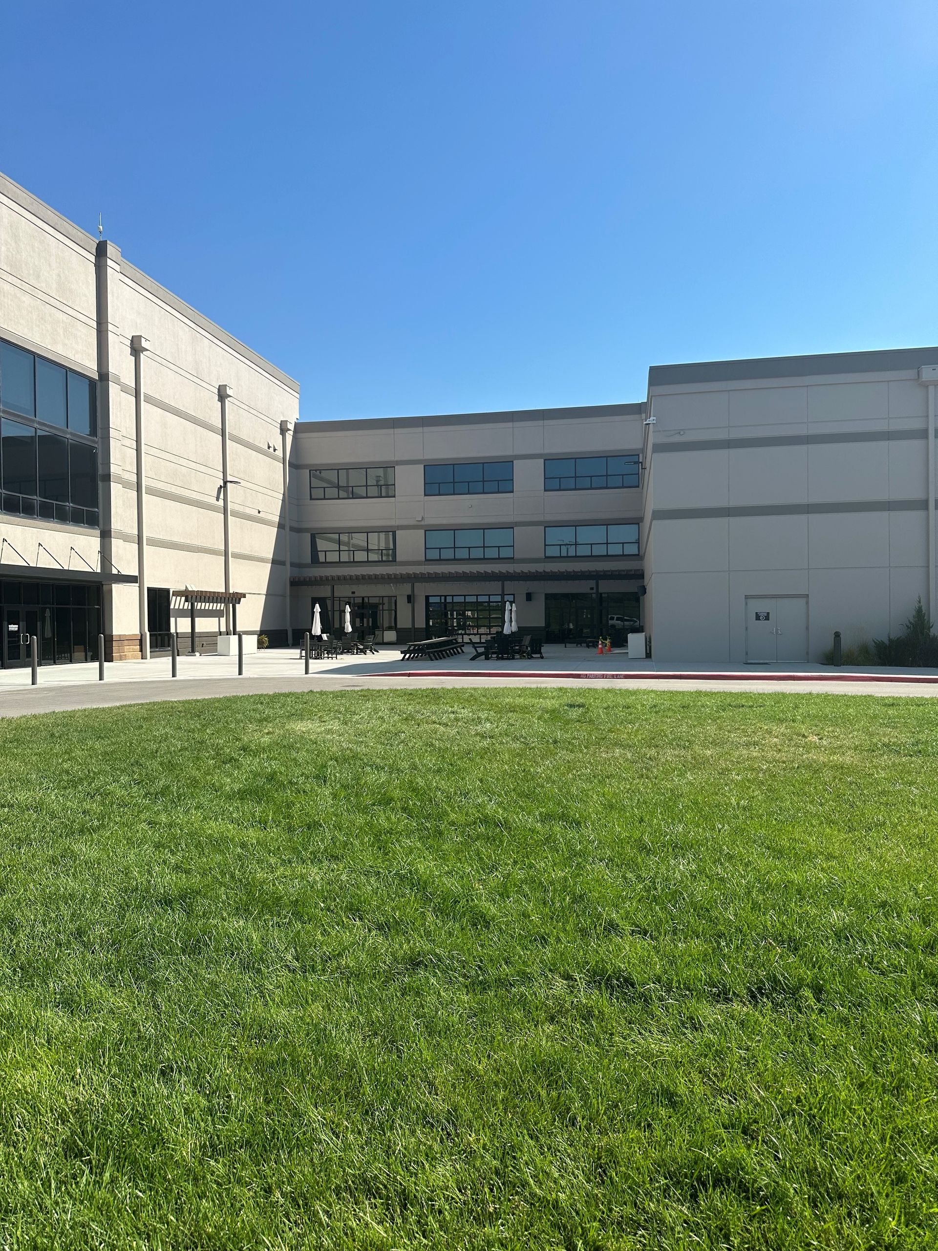 Modern building courtyard with green lawn under a clear blue sky
