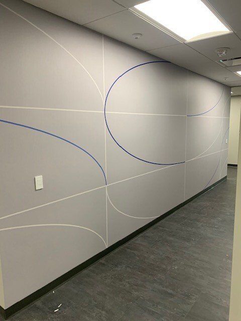 Empty office hallway with gray walls, white wavy lines, and a ceiling light overhead