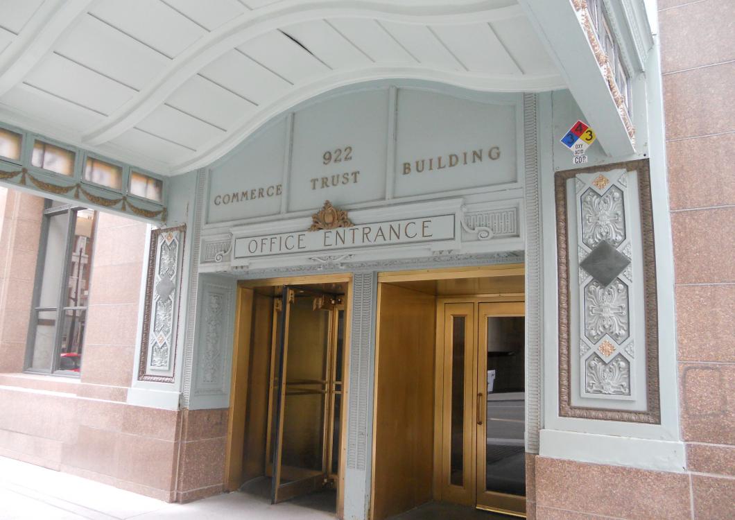 Building entrance with gold doors and stone archway under a white covered walkway