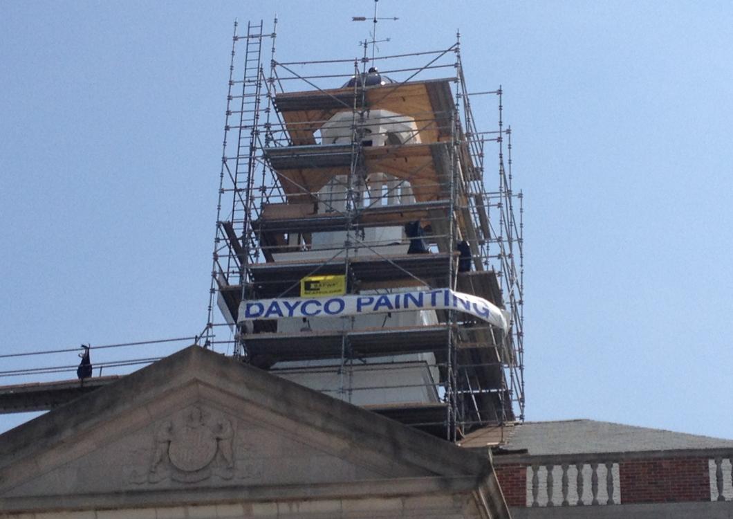 Scaffolded tower with a blue “DAYCO PAINT” banner above a building roofline