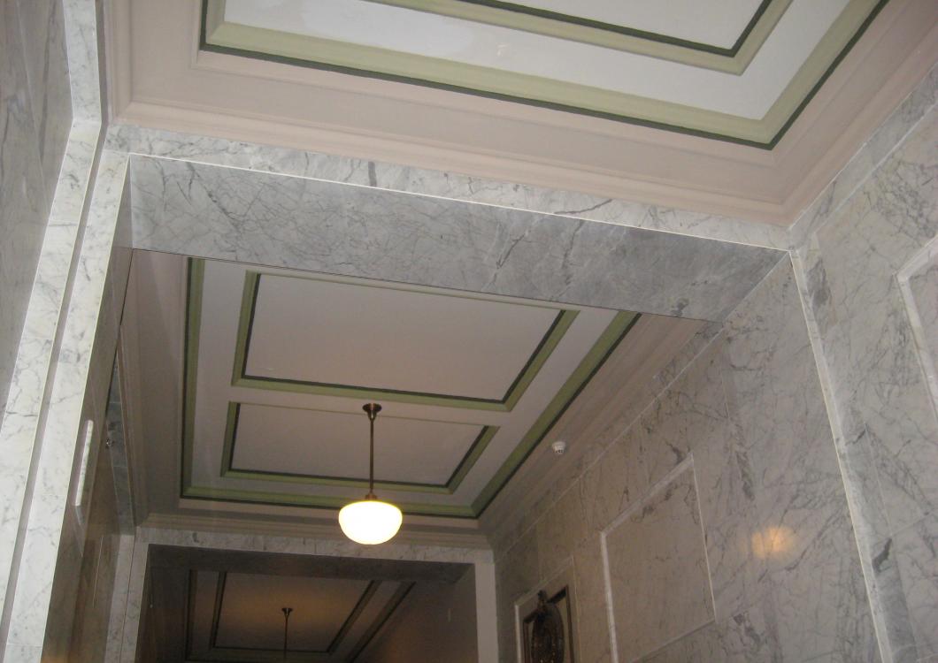 Marble hallway with decorative ceiling panels and a hanging light fixture