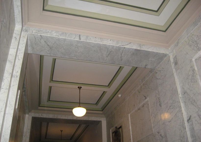 Marble hallway with decorative green-trimmed ceiling and hanging light fixtures