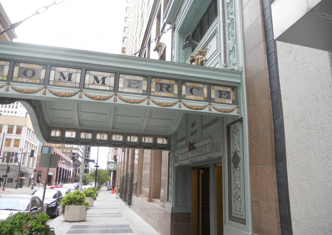 Decorative teal awning over a city sidewalk beside a building entrance and planters