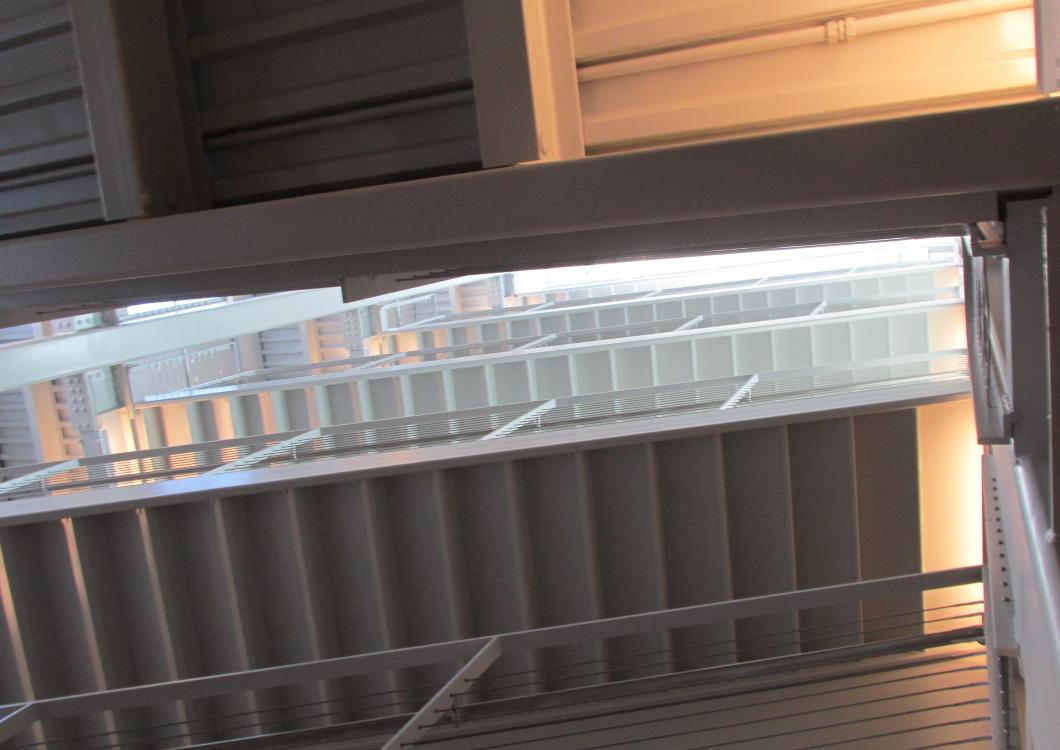 Metal shelf in front of a window with blinds, lit by warm sunlight.