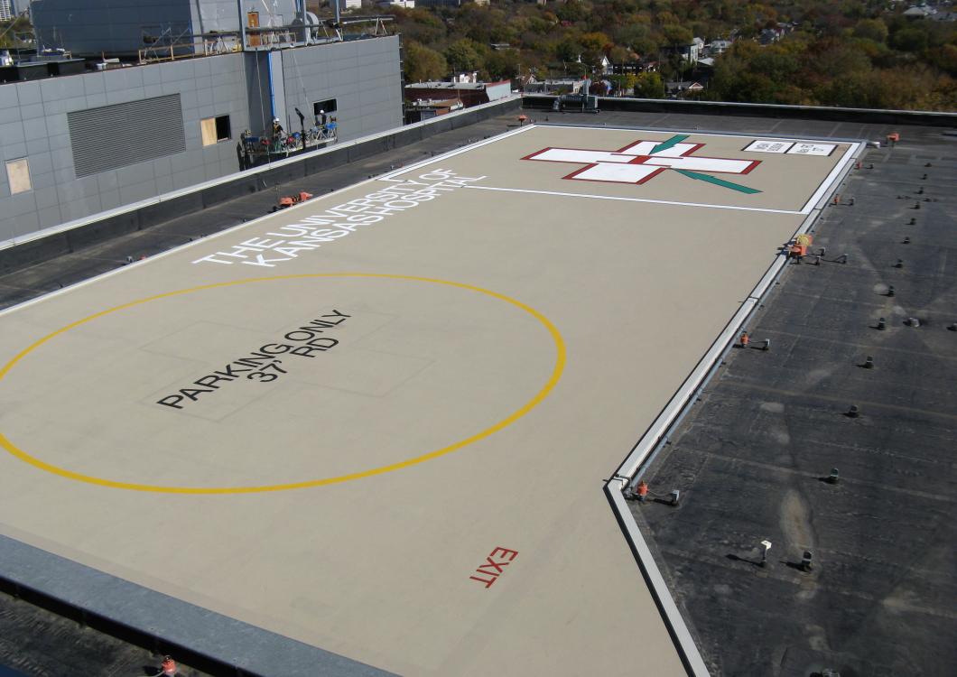 Rooftop helicopter landing pad with a yellow circle and large white and red marking.