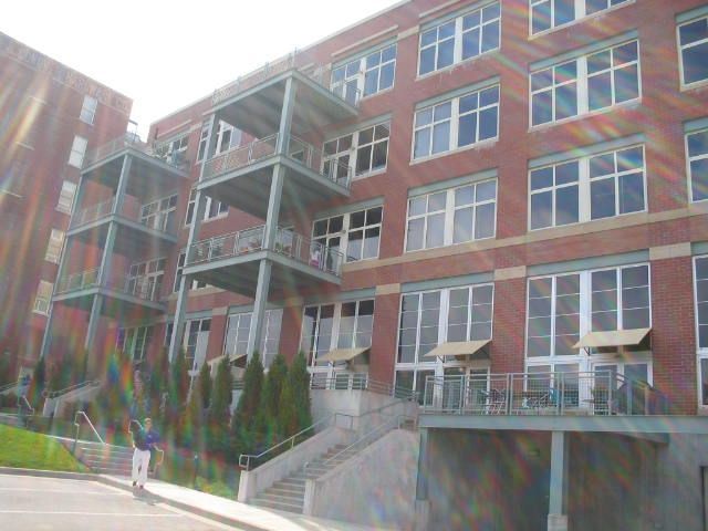 Brick apartment building with balconies, stairway, and sun glare