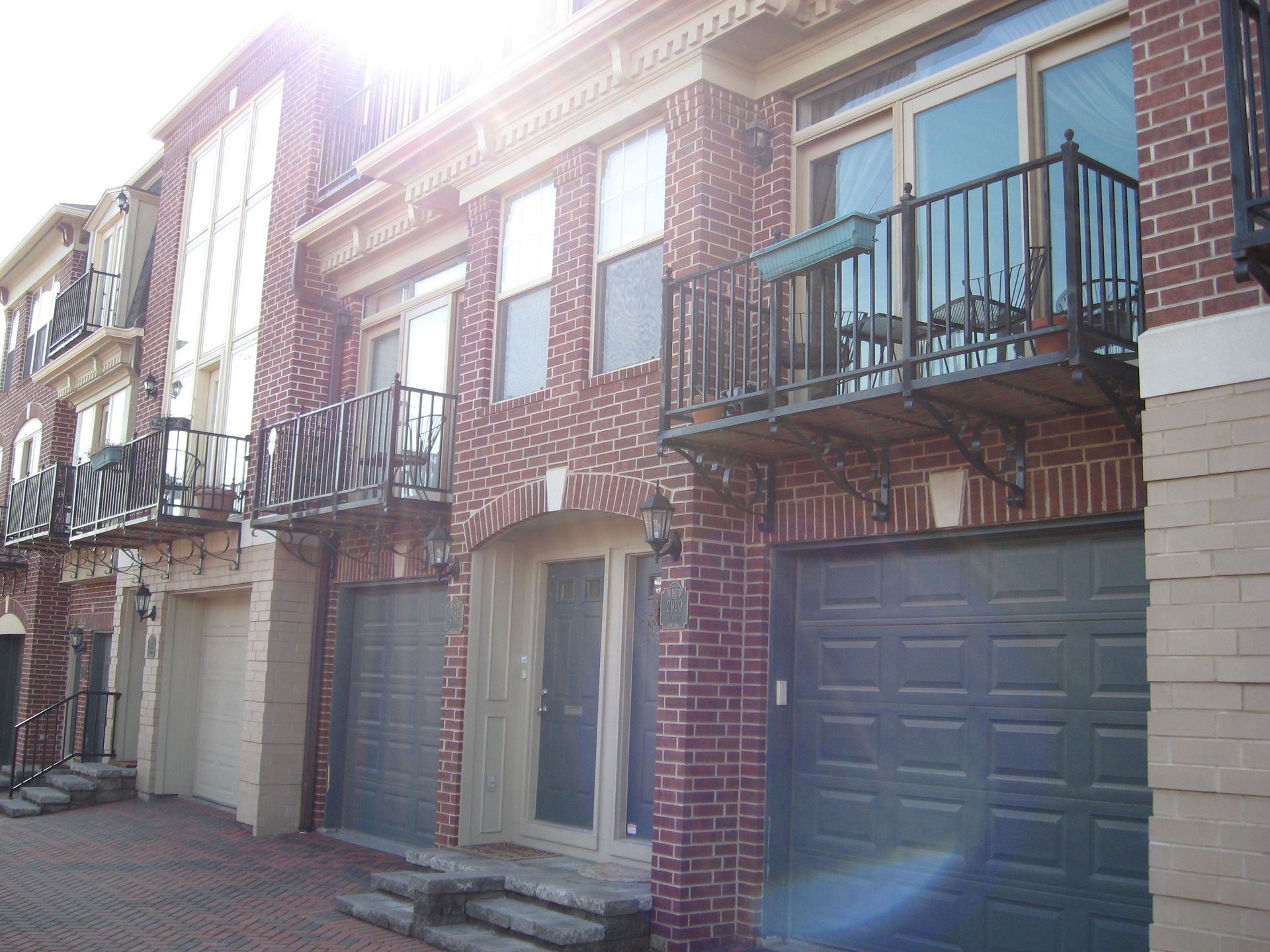 Brick row houses with garages and balconies on a sunny street