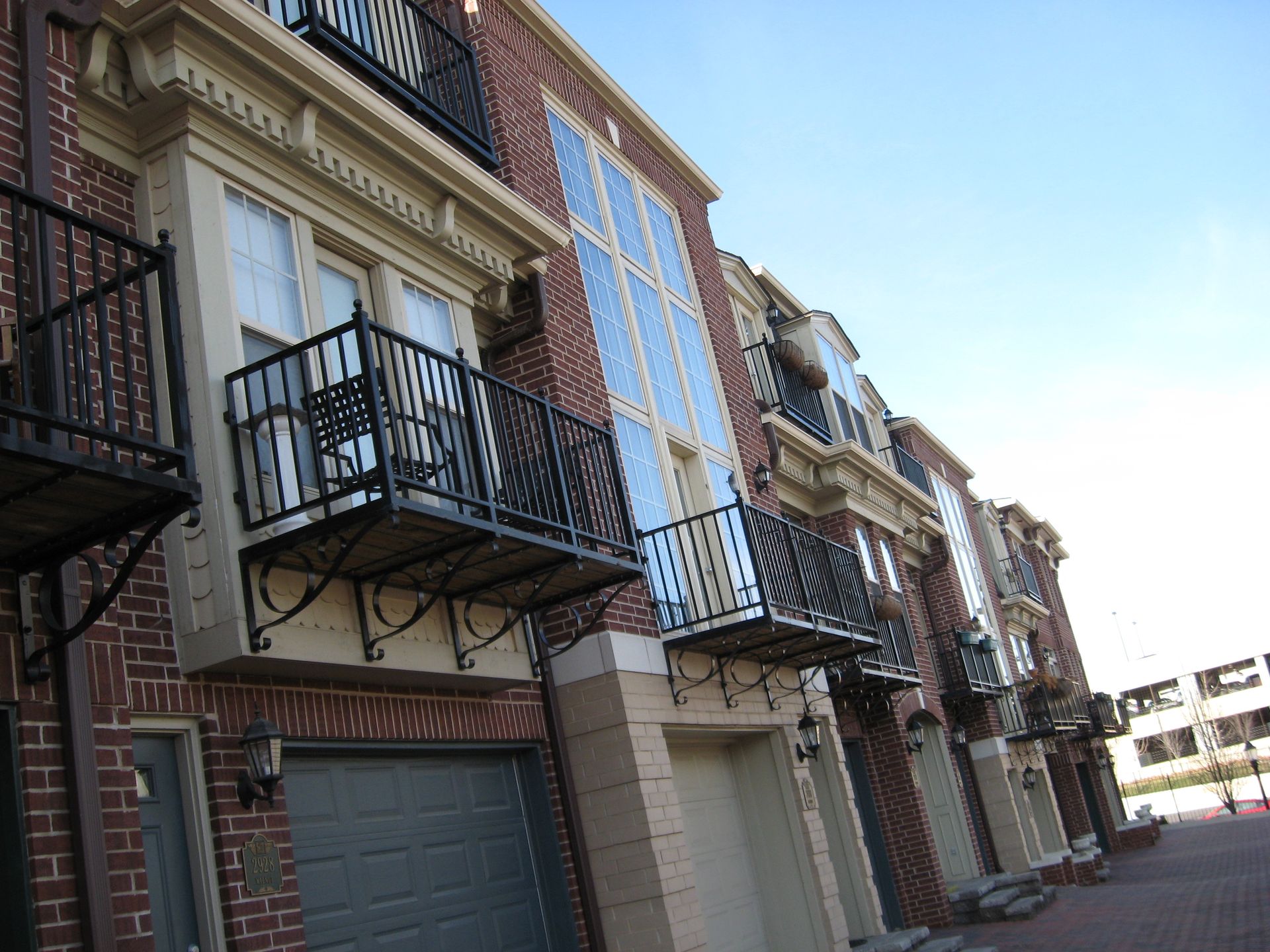 Row of brick townhouses with wrought-iron balconies on a sunny street