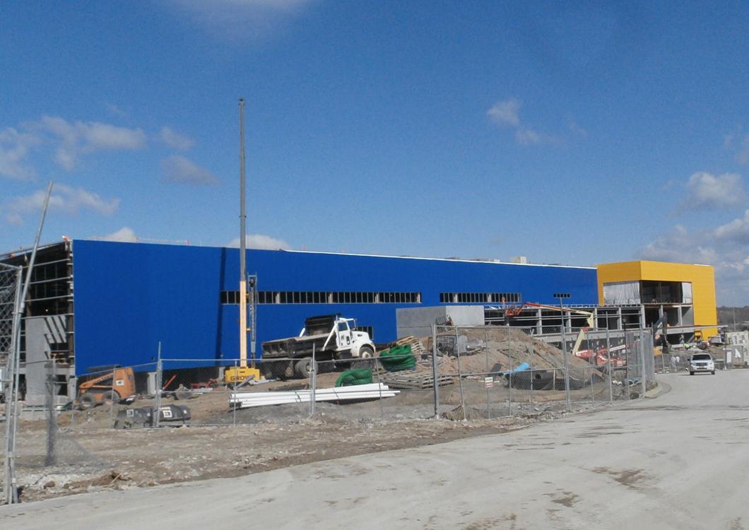 Blue industrial building under construction with rubble and equipment in the foreground