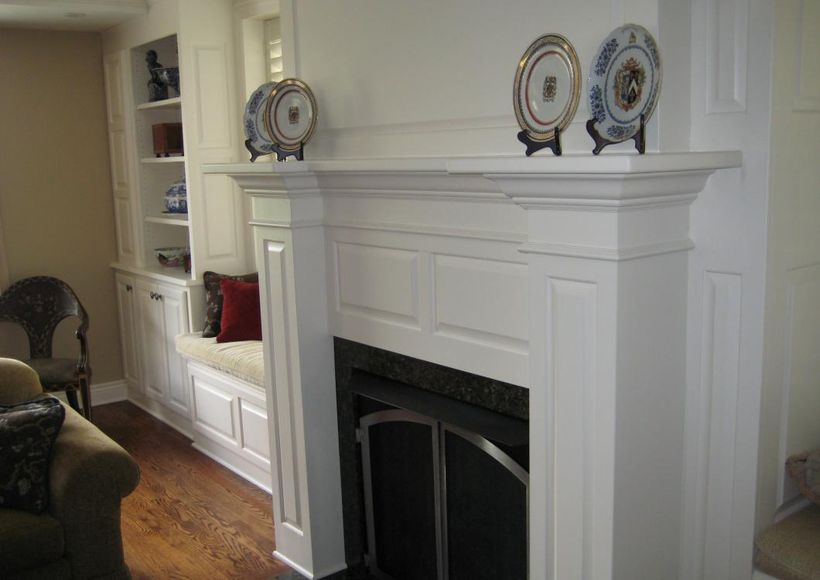 White living room fireplace with mantel decor and built-in bench seating on the left
