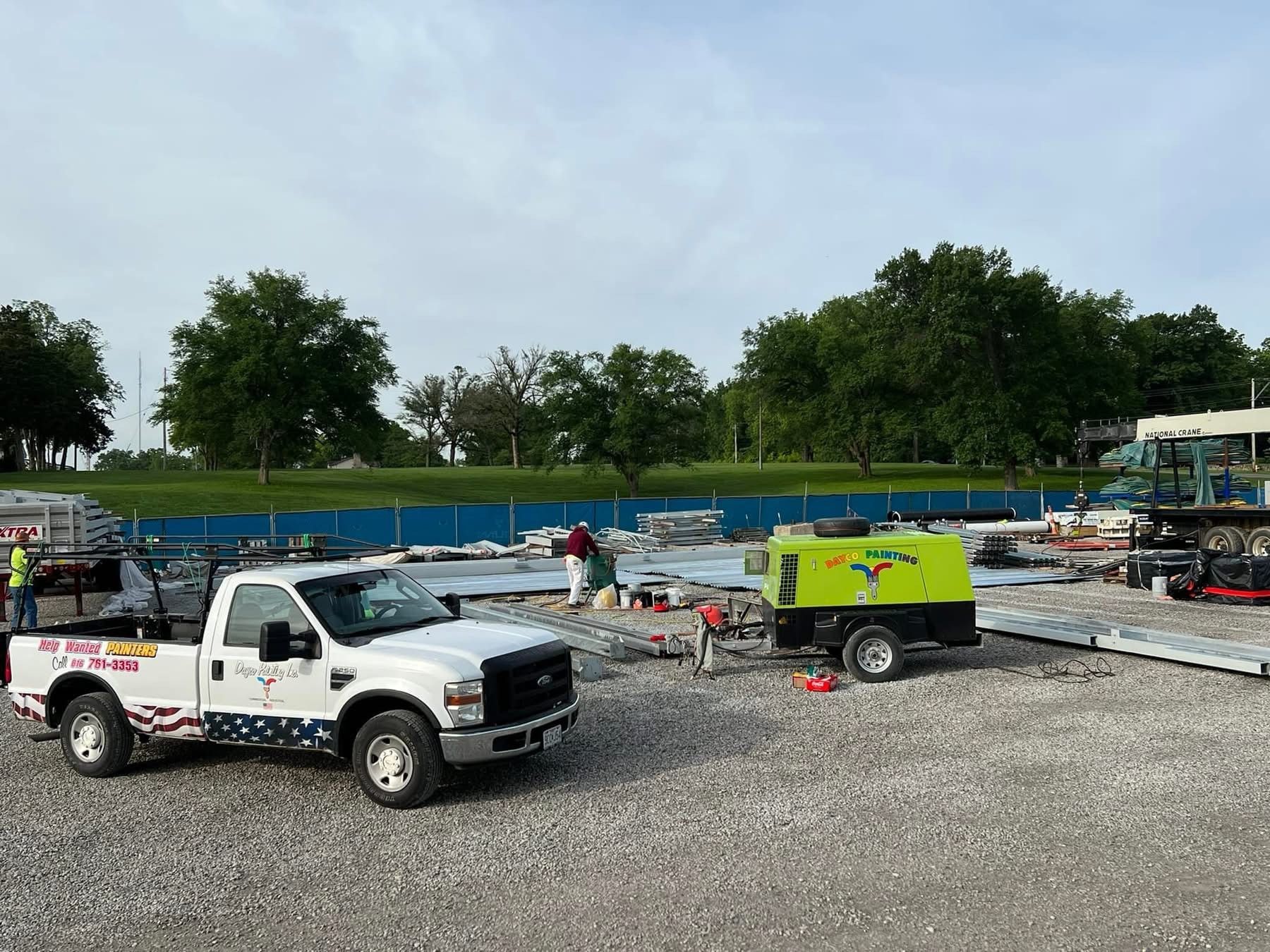 White pickup truck and green trailer on gravel beside a blue-lined pool under construction outdoors