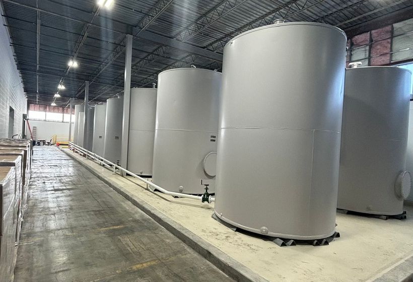 Large industrial room with rows of tall gray cylindrical tanks along a concrete floor
