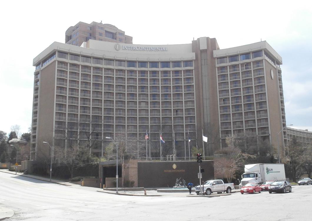Large curved hotel building in winter, with snow-covered ground and parked cars in front