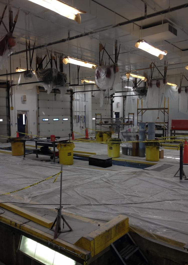 Industrial workshop with yellow buckets and hanging equipment under bright ceiling lights