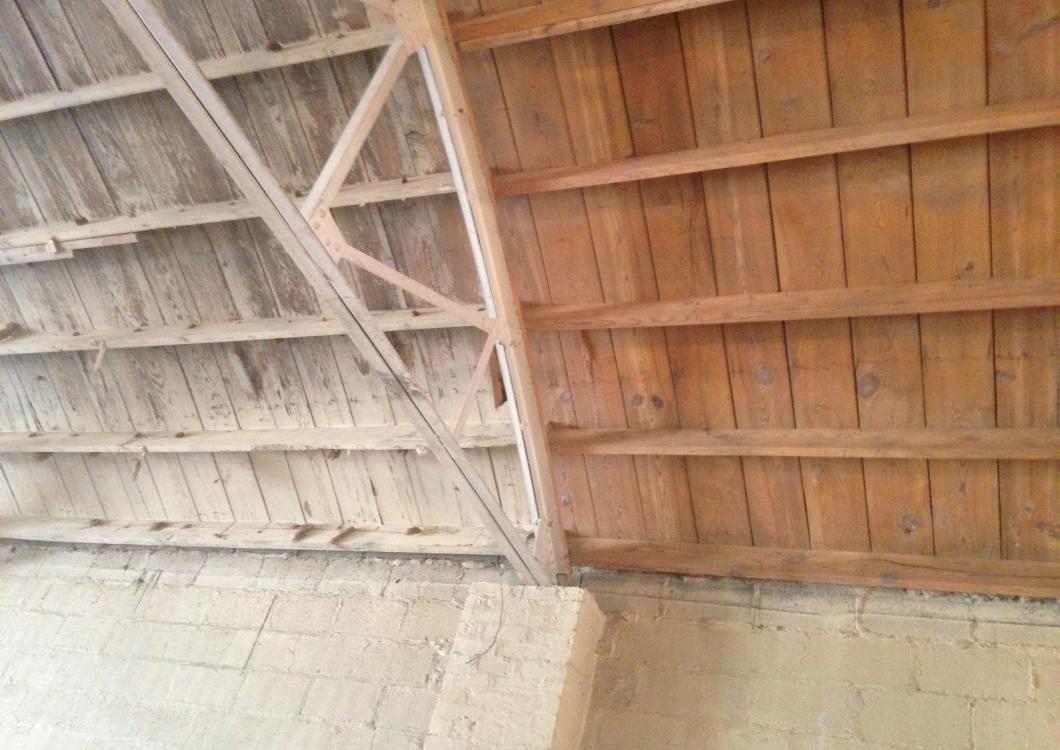 Wooden roof rafters and slanted ceiling with beige walls underneath