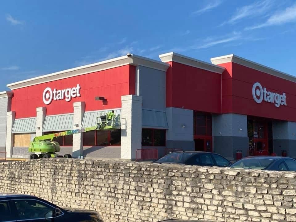 Target store exterior with red facade and parked cars behind a stone wall