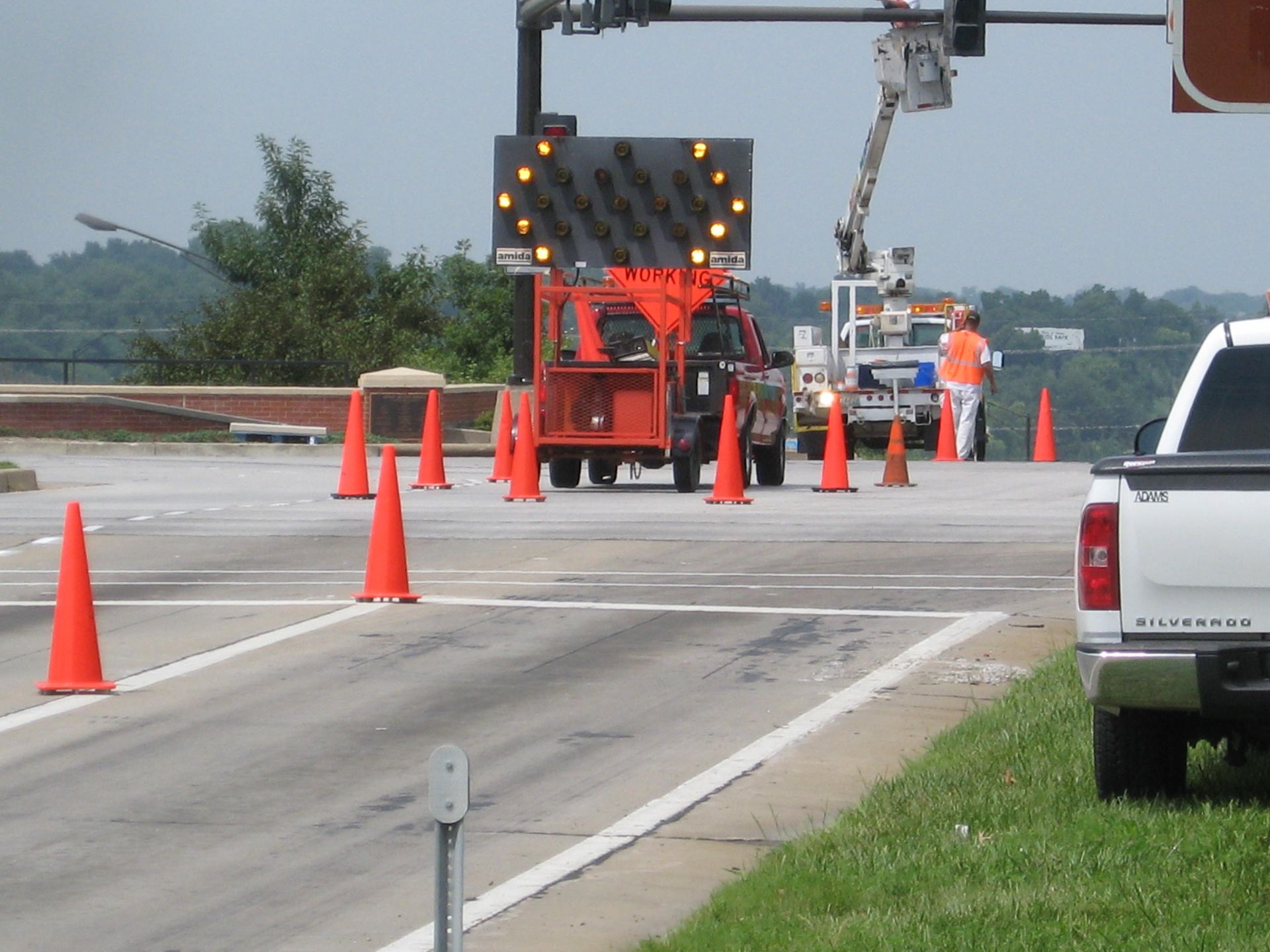 Roadwork on a highway with orange cones, a red utility truck, and workers near a lane closure