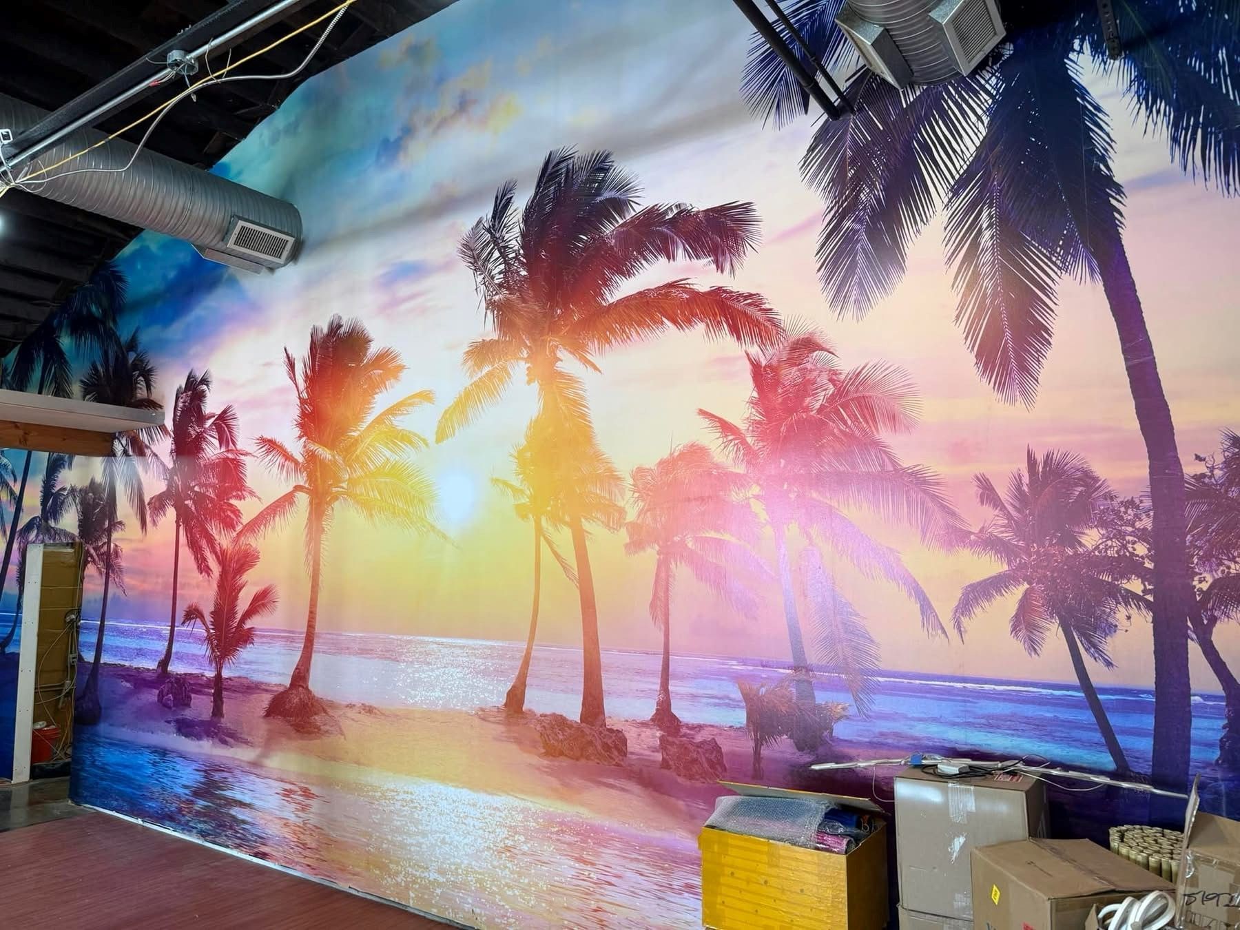 Colorful mural of a tropical beach sunset with palm trees and ocean reflections indoors