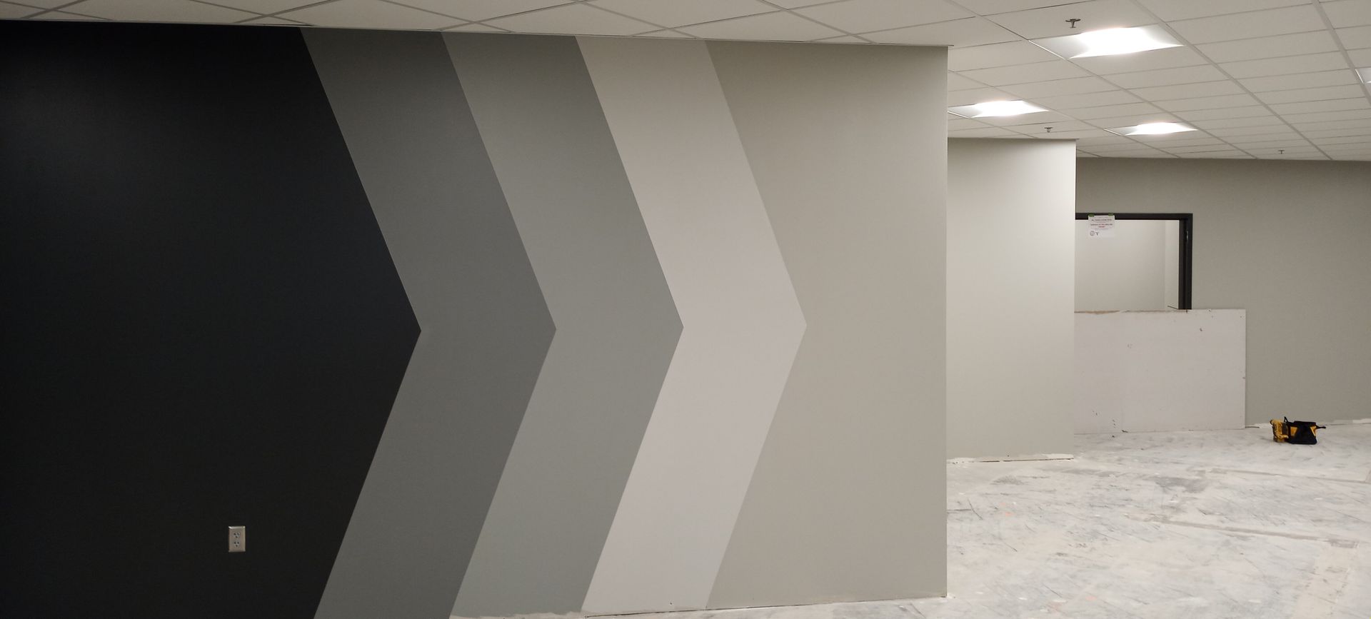 Modern interior with a dark-to-light geometric painted wall and open office hallway