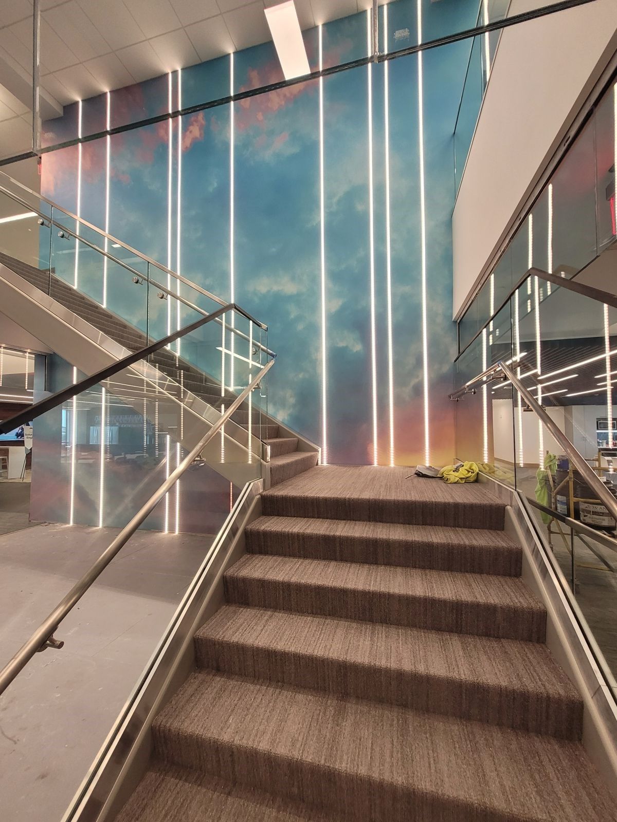 Indoor stairway with glass railings and a tall blue wall in a modern building