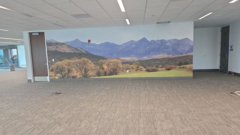 Empty office lobby with carpeted floor and a large mountain landscape mural on the back wall