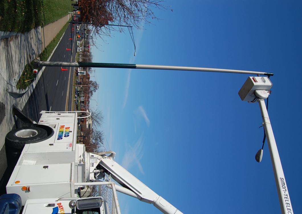 Utility truck with raised bucket near a road under a clear blue sky