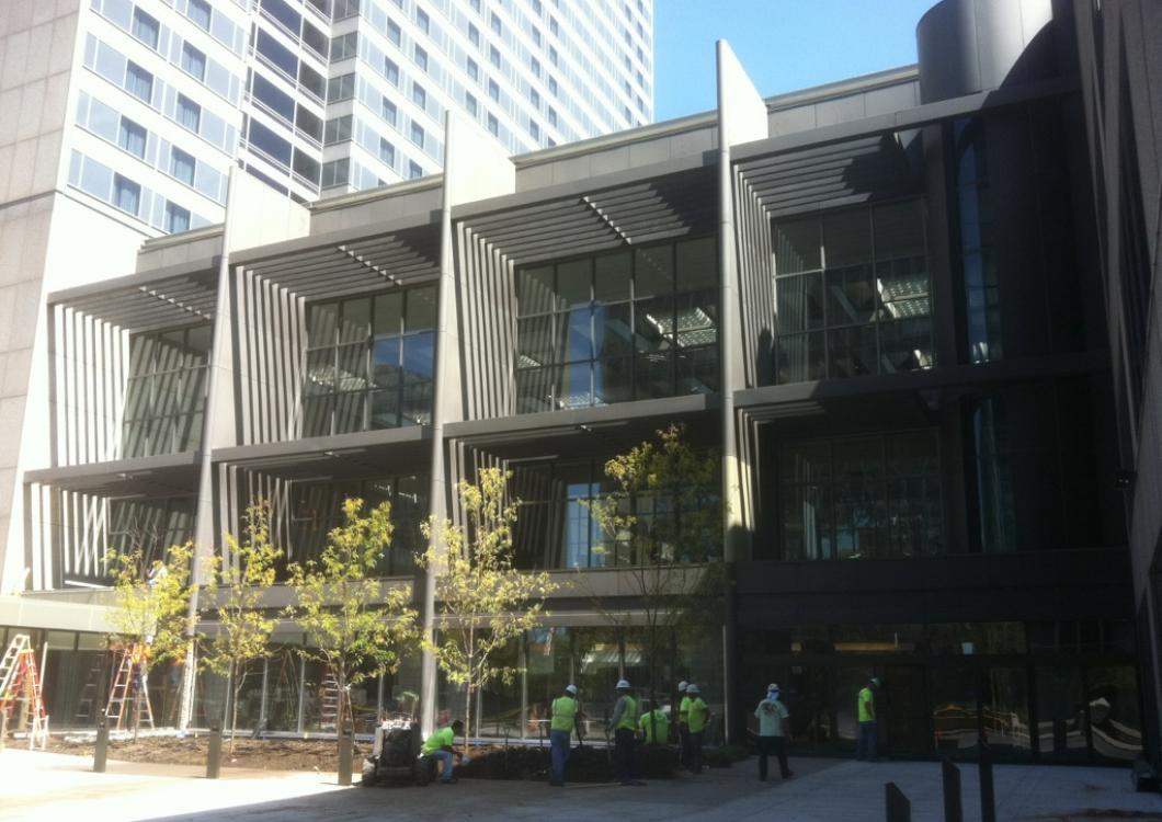 Modern building facade with glass-fronted balconies and a shaded sidewalk below.