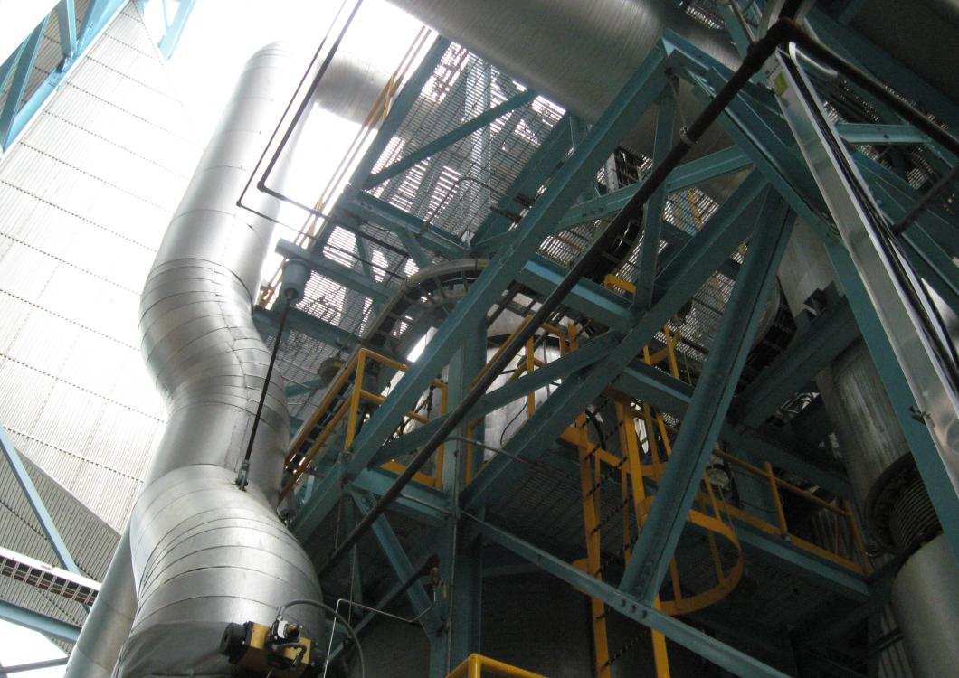 Industrial metal stairwell with silver ducting and blue steel beams inside a factory