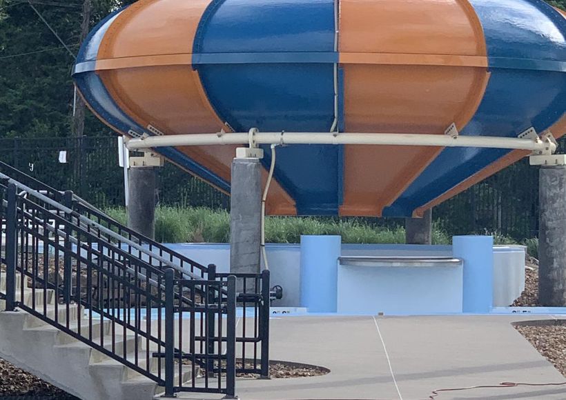Orange and blue water slide structure beside stairs in an outdoor park area