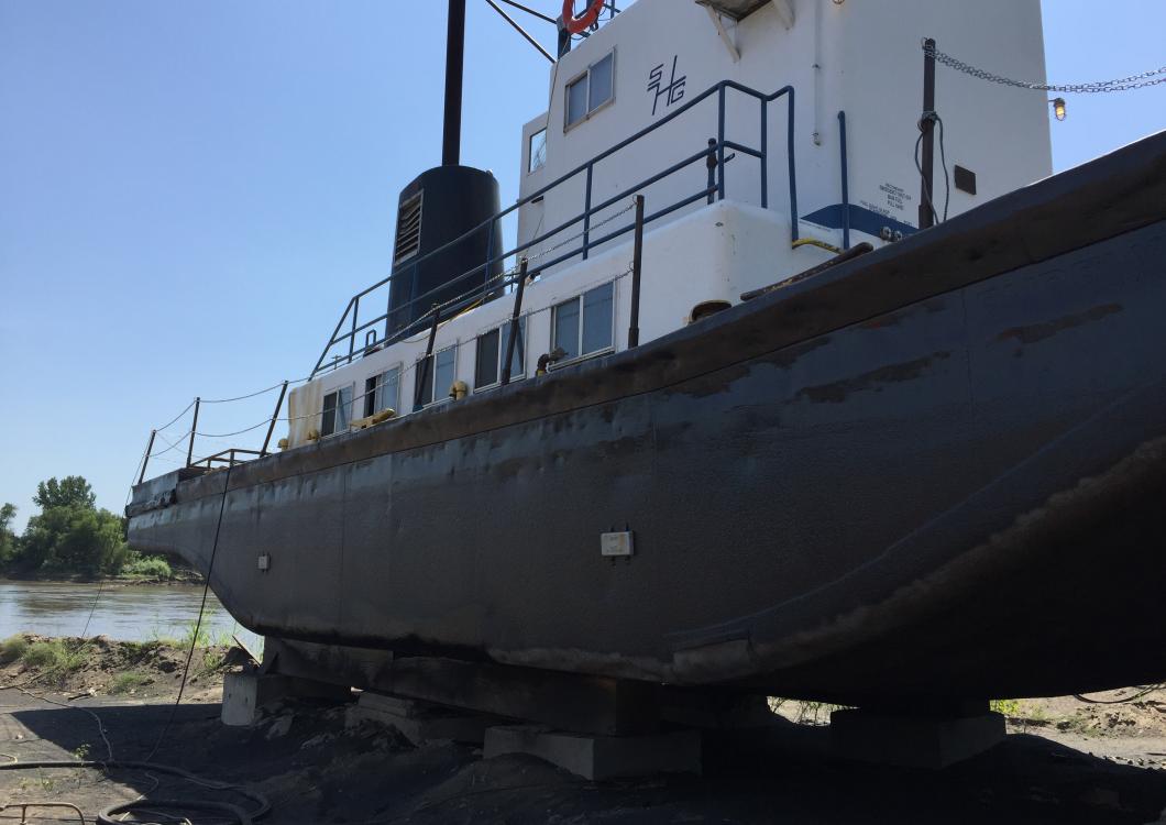 Large black-and-white ship hull on land with railings and an upper cabin under a clear blue sky