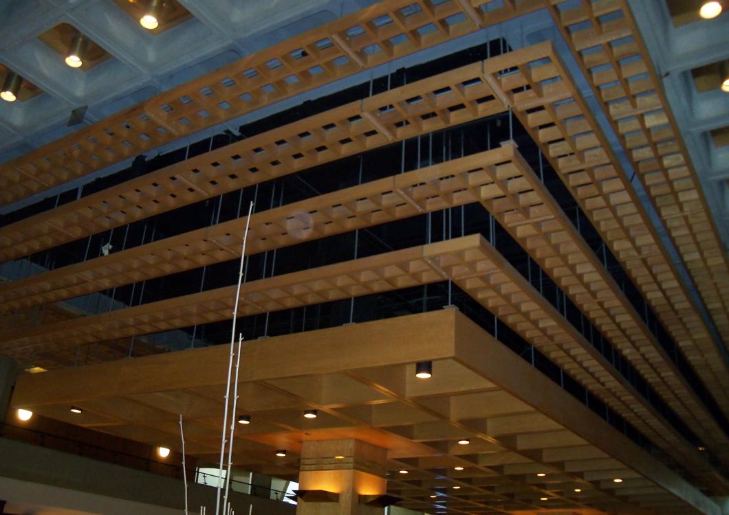 Modern indoor atrium with a suspended geometric metal ceiling installation and warm lights below