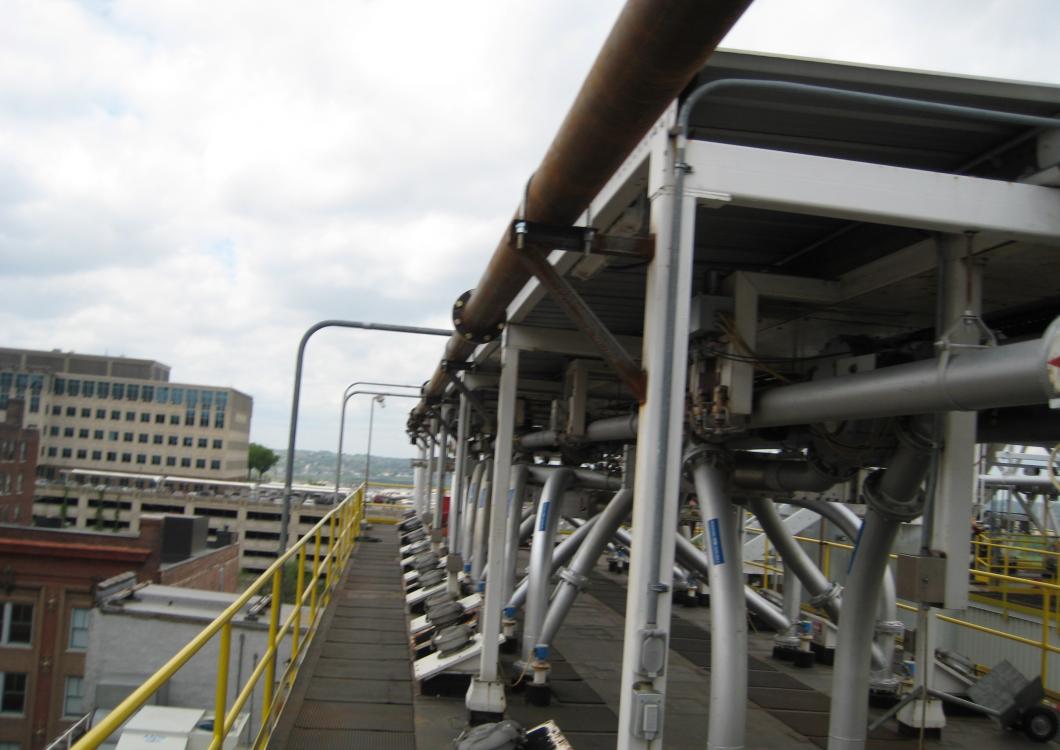 Industrial catwalk with yellow railings and large metal pipes at an outdoor facility