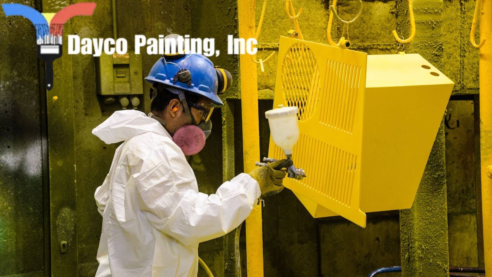 hiring painters A hired painter wearing a hard hat is spray painting a yellow wall .