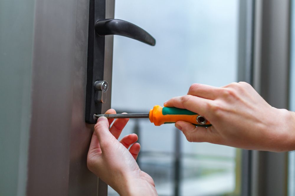 Closed Up Of A Person Is Fixing A Door With A Screwdriver — Ezi Slide - Glass, Sliding, Track & Security Doors Repair in Ashmore, QLD