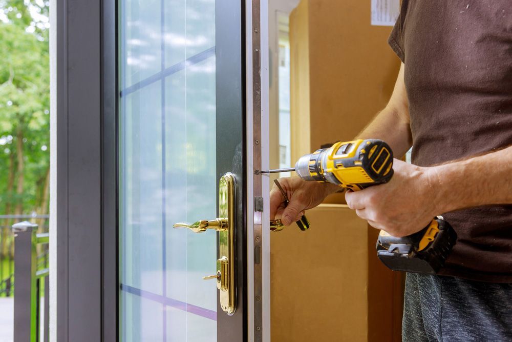 A Man Is Fixing A Door With A Drill — Ezi Slide - Glass, Sliding, Track & Security Doors Repair in Gold Coast, QLD