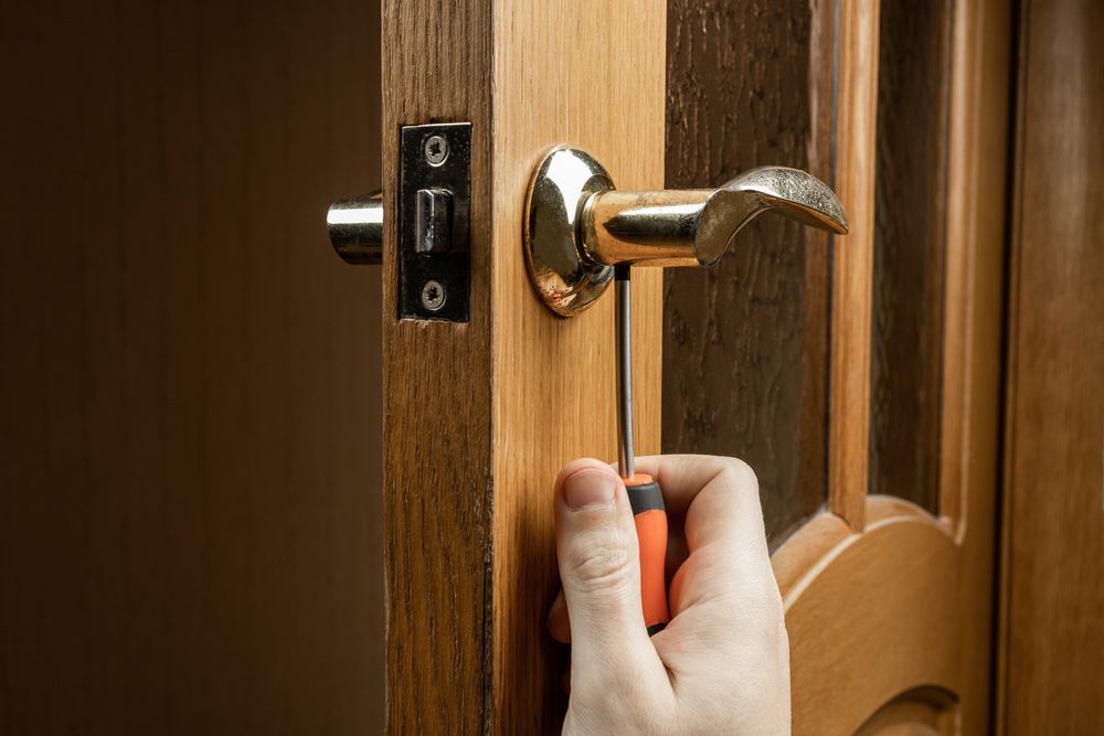 A Person Is Repairing A Door Handle With A Screwdriver — Ezi Slide - Glass, Sliding, Track & Security Doors Repair in Ashmore, QLD