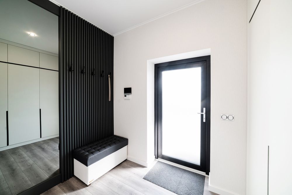 A Hallway With A Black Door And A Bench — Ezi Slide - Glass, Sliding, Track & Security Doors Repair in Gold Coast, QLD