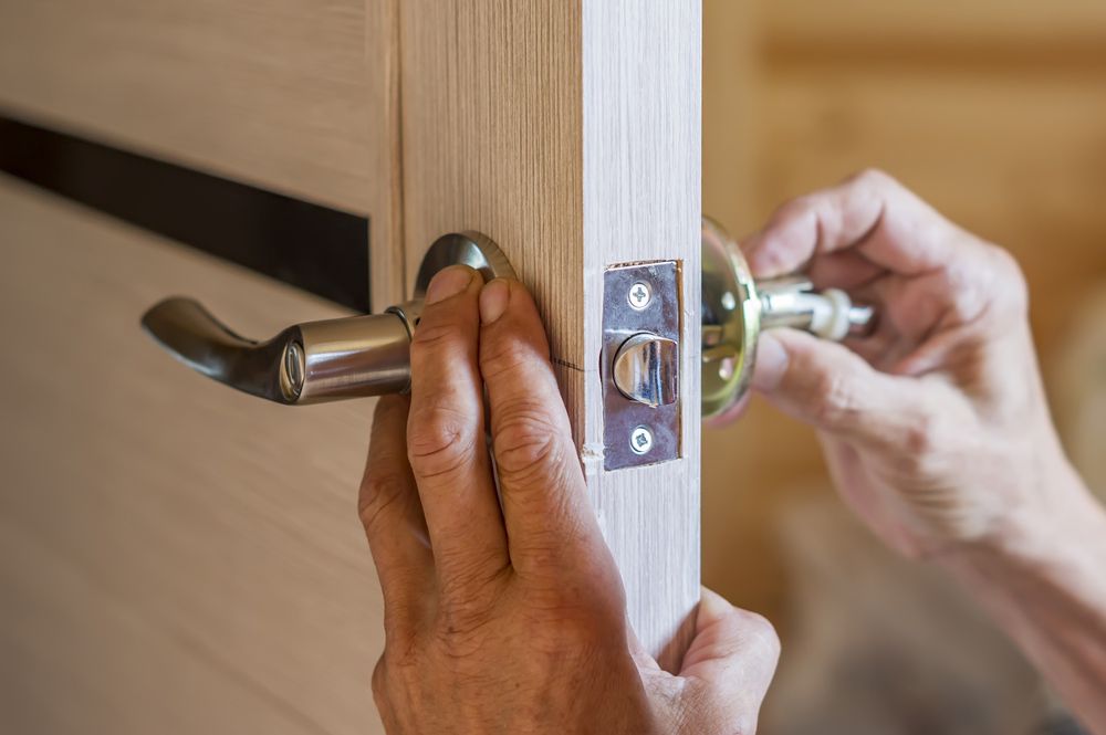 A Person Is Installing A Door Handle On A Wooden Door — Ezi Slide - Glass, Sliding, Track & Security Doors Repair in Ashmore, QLD