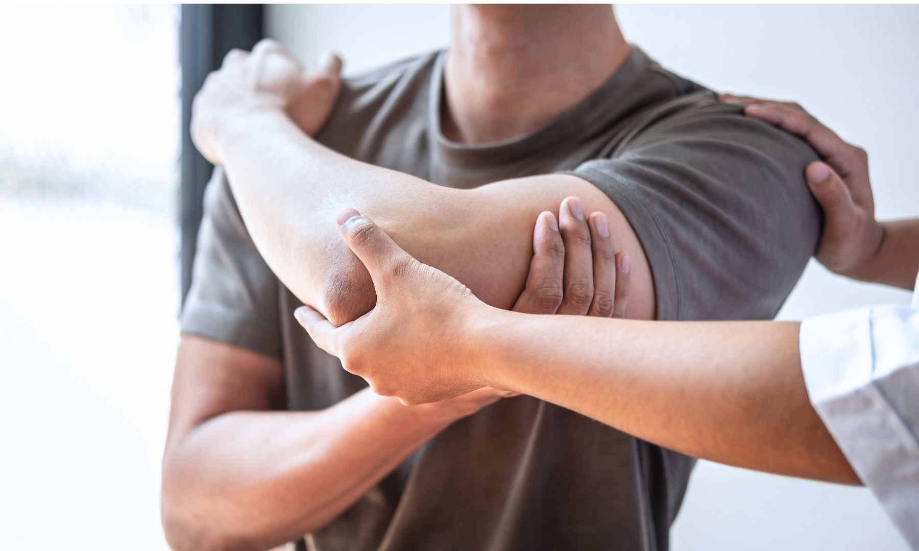 A man is getting his elbow examined by a doctor.