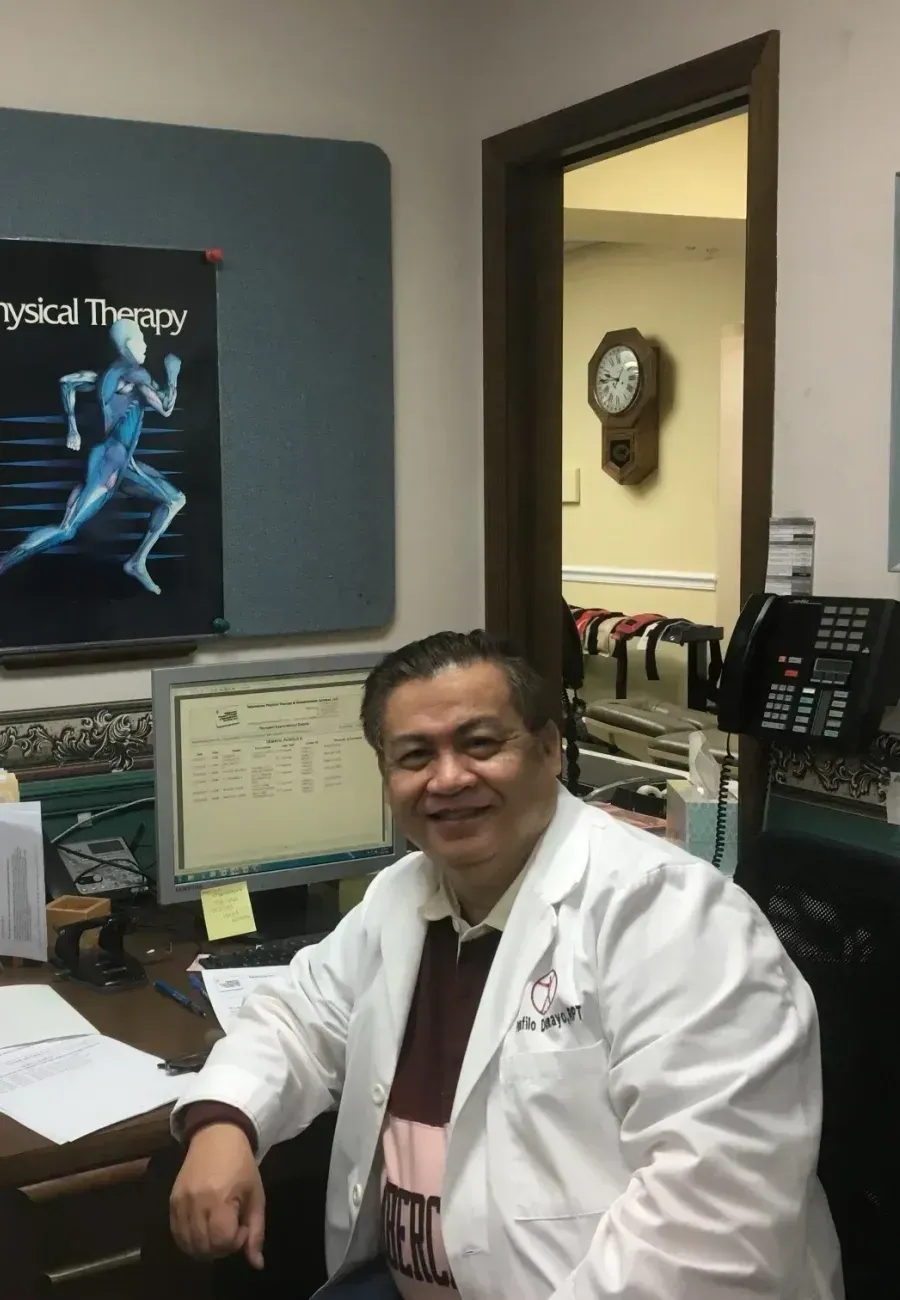 A man in a lab coat is sitting at a desk in front of a computer.