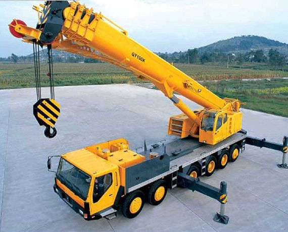 Grúa hidráulica levantando una carga pesada en una obra de construcción.