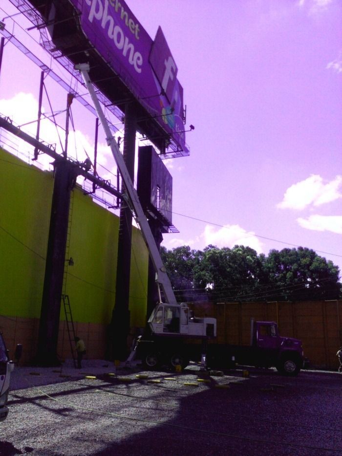 Edificio de color púrpura con un camión con escalera y una plataforma elevadora trabajando afuera de una tienda de teléfonos.