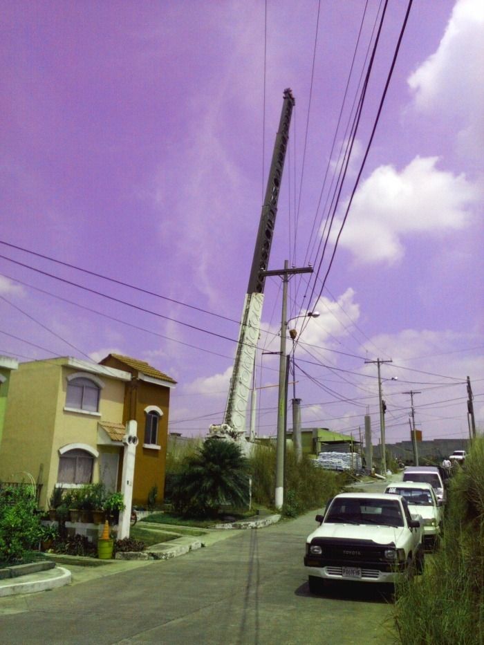 Calle residencial con coches aparcados, postes de luz y un cielo de tonalidad púrpura.