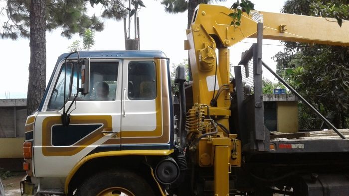 Un camión grúa amarillo estacionado junto a un camión de plataforma en una calle.
