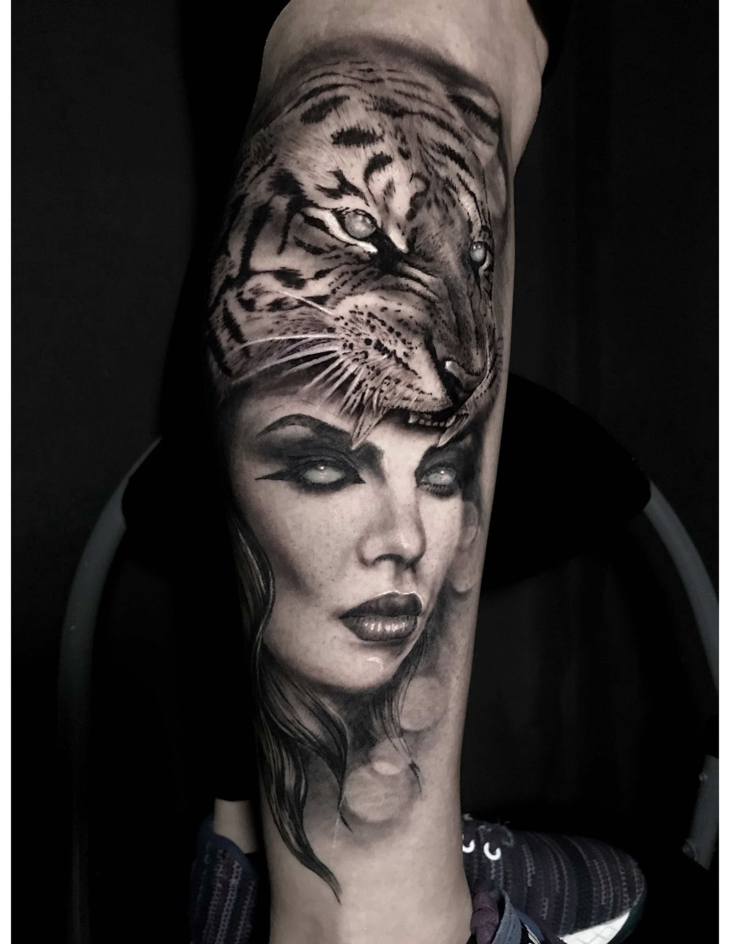 Tattoo of a woman's face with a tiger's head overlayed on her, black and white.