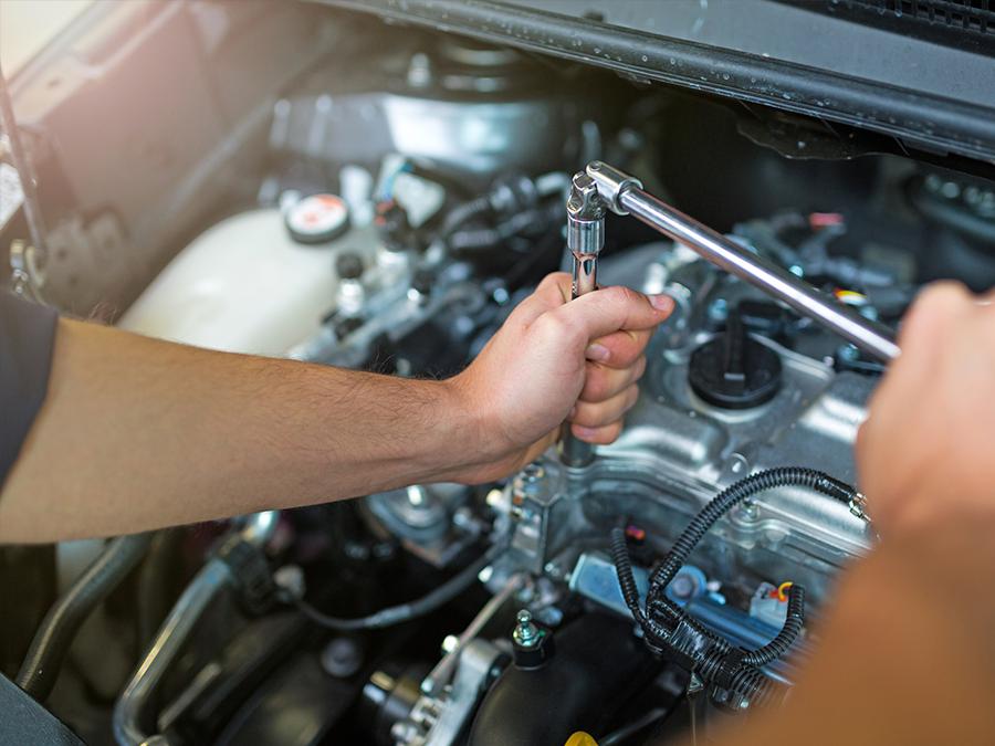 A man is working on a car engine with a wrench.