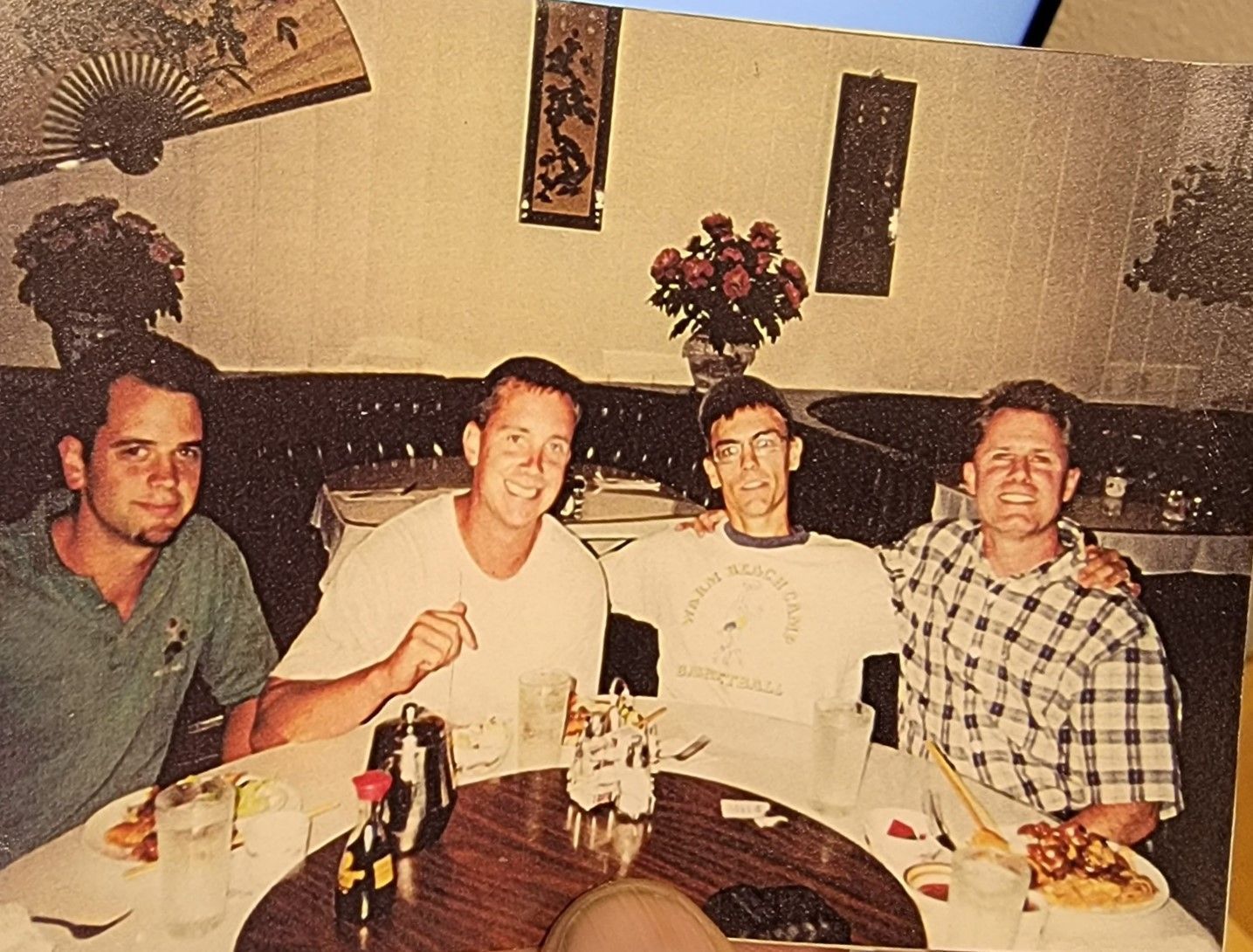 Four men smile while seated at a round table in a Chinese restaurant. 