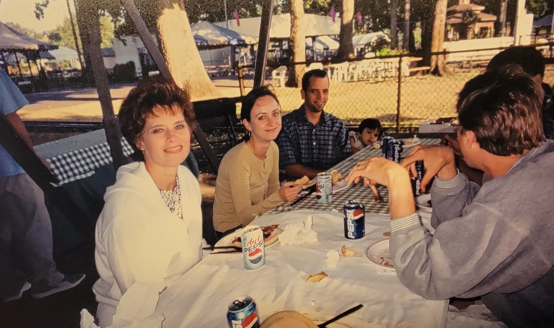 A group of people seated at a picnic table outdoors. 