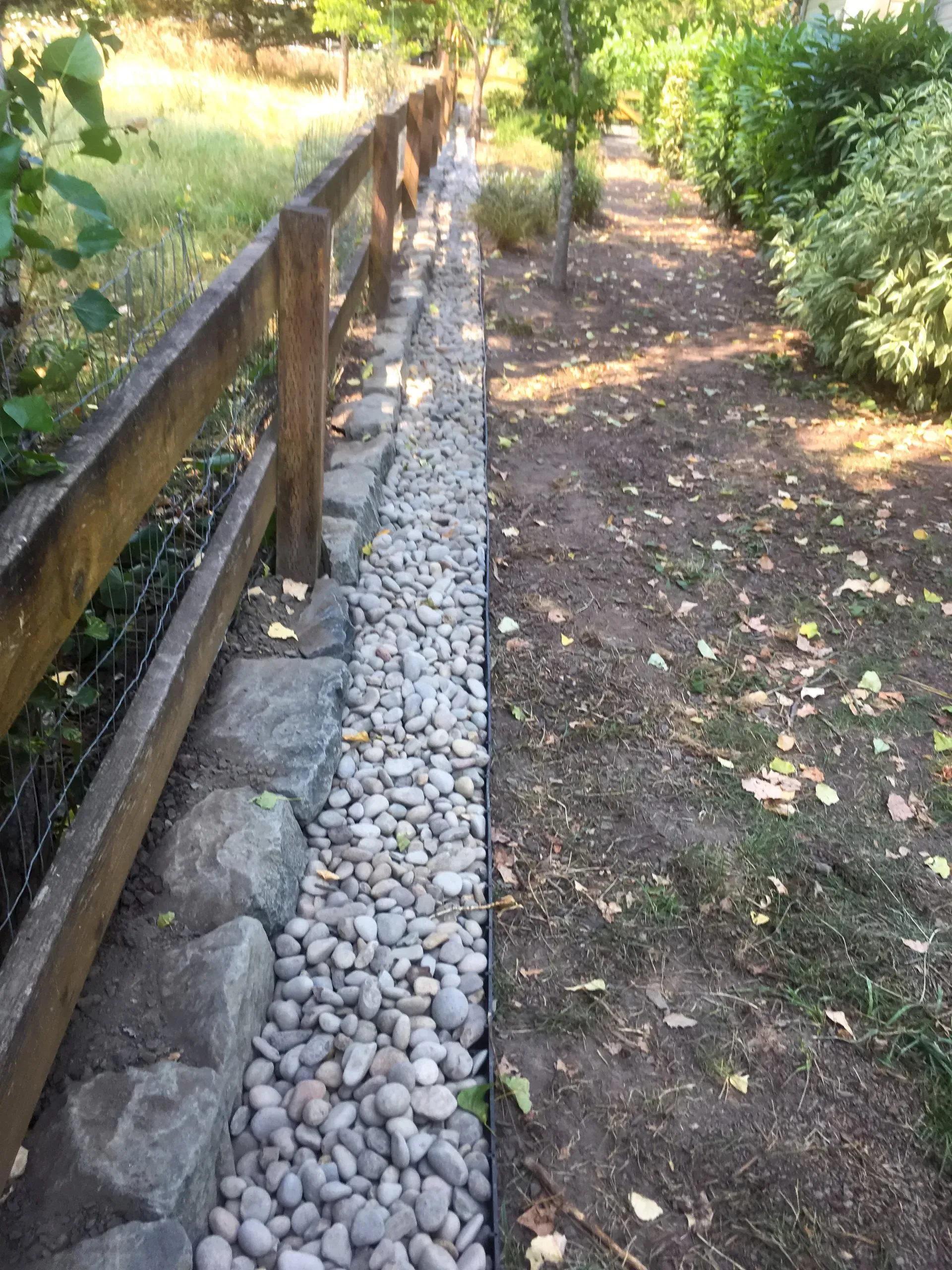 A gravel-lined path alongside a wooden fence. 