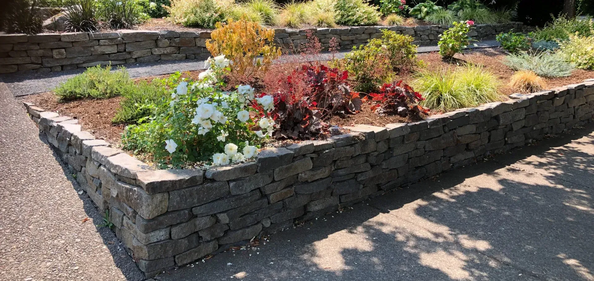 A stone-walled garden bed filled with various plants and flowers. 